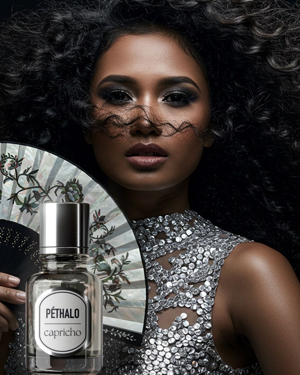An image of a dark-skinned Filipina model wearing a silver dress and holding a mother-of-pearl decorated fan. Shown on the side is a Capricho extrait de parfum bottle.